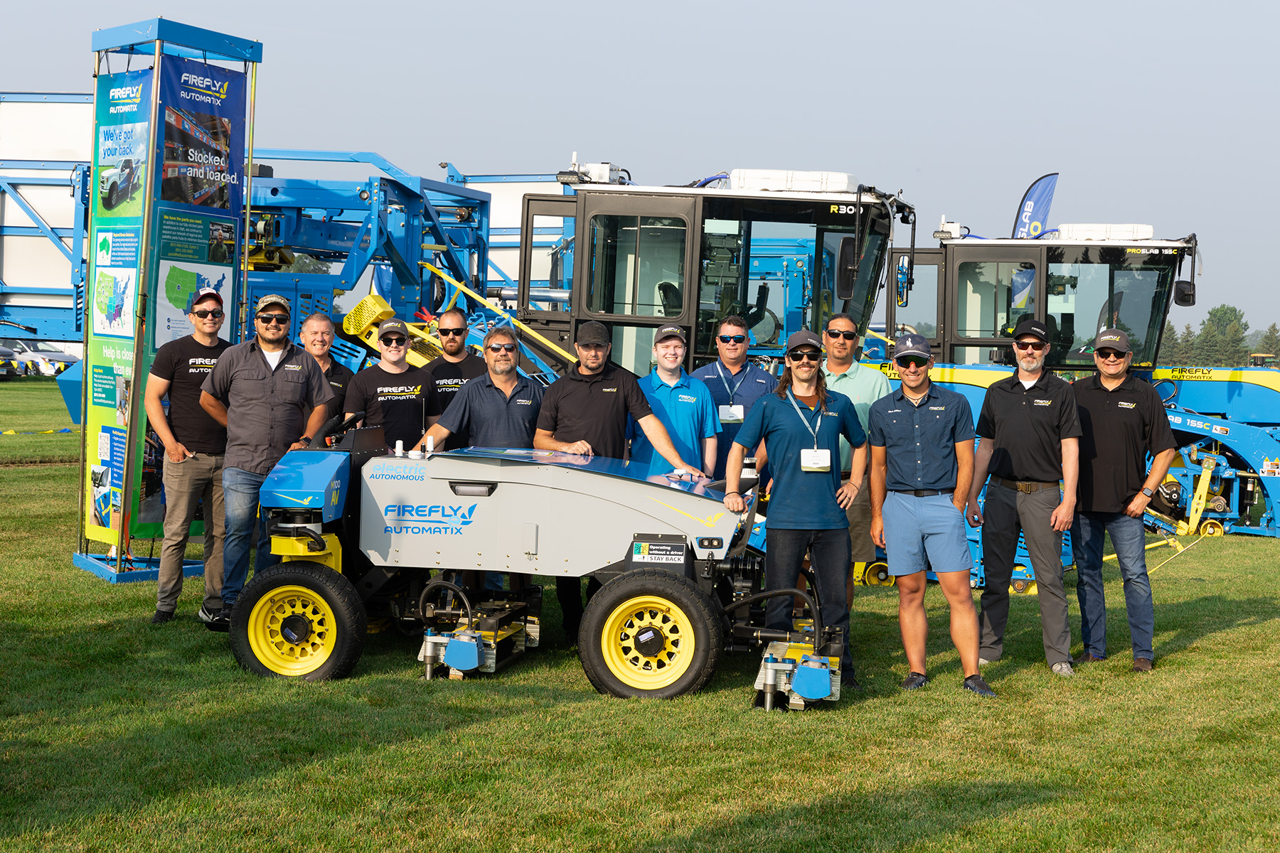 Several team members in front of FireFly autonomous lawn mower and sod harvesters
