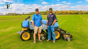 Eric Hjort and Gage Hjort in front of FireFly autonomous mower in grass field at Tater Farms