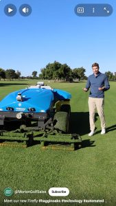 robotic fairway mower on green grass with a man standing next to it